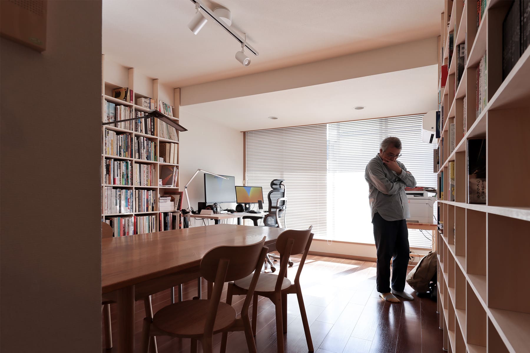 リビングダイニングの壁2面にそれぞれ「Shelf 壁一面の本棚 奥行250mm」及び「Shelf 壁一面のA5判本棚 奥行180mm」を向かい合う形で置かれています。